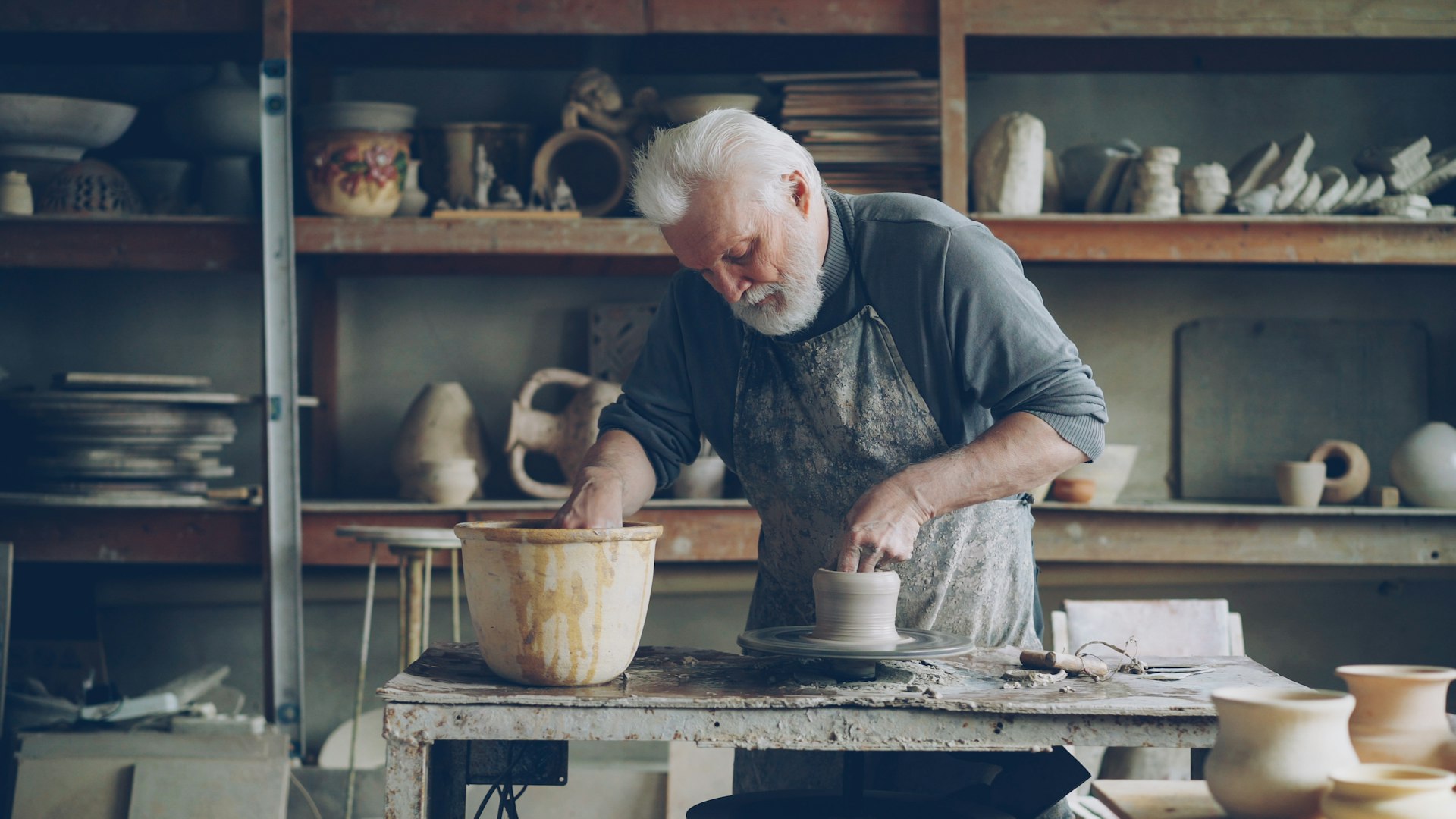 A potter molds clay in his workshop.